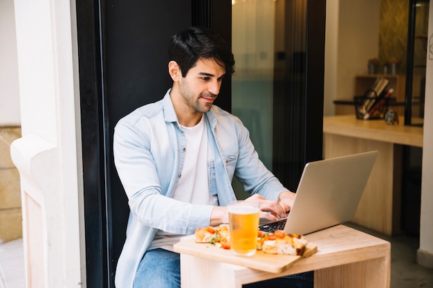 Macho sentado no café com laptop