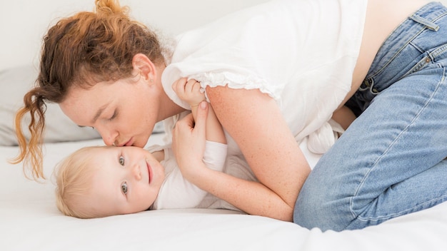 Foto grátis mãe adulta, beijando seu bebê