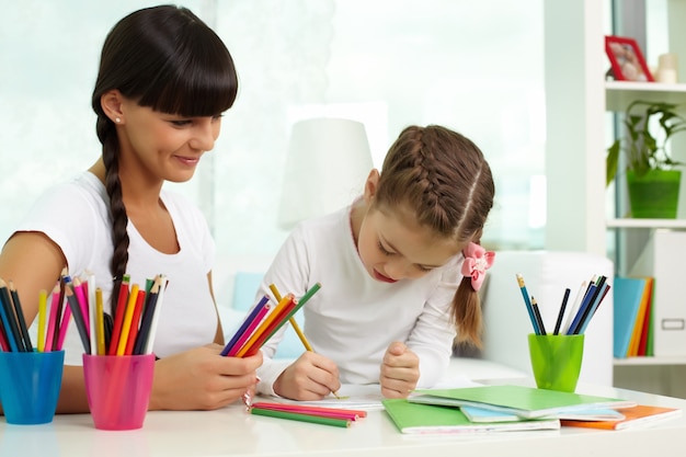 Mãe ajudando a filha para desenhar