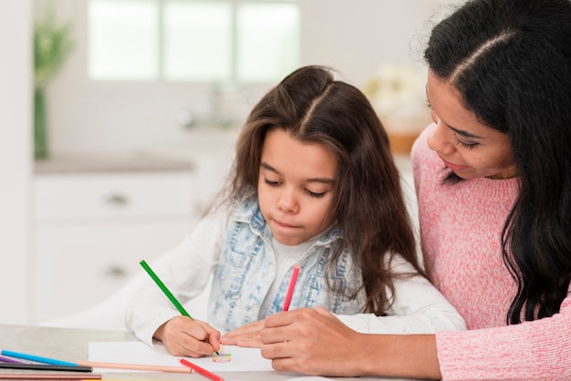 Mãe, ajudando a garota a colorir o livro