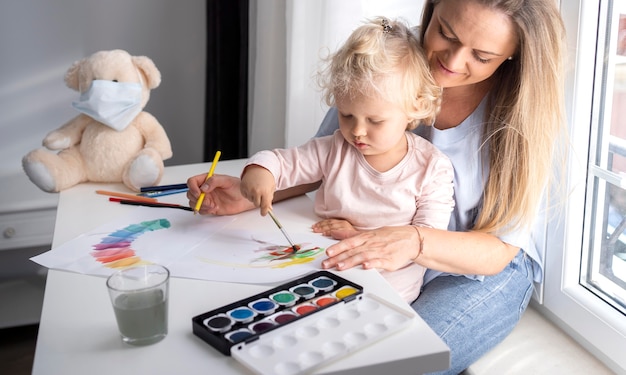 Mãe ajudando criança a pintar em casa