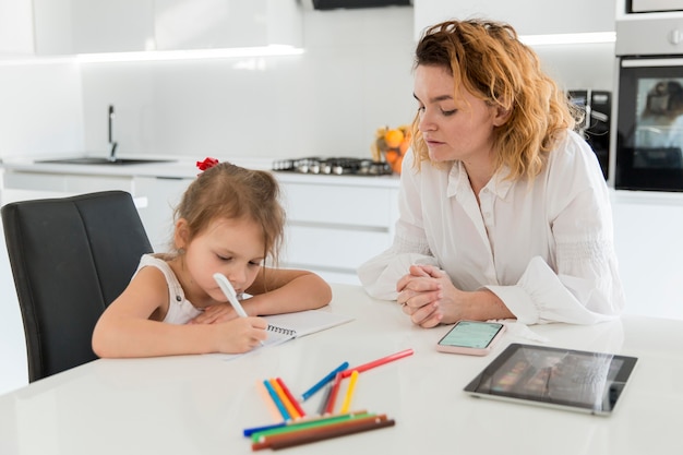 Mãe ajudando filha com lição de casa