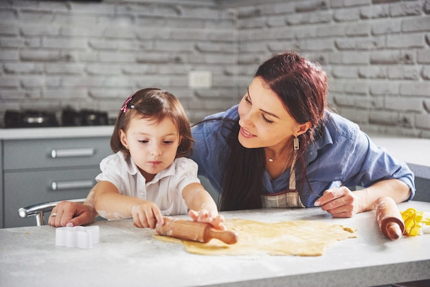 Mãe amando o forno para a filha do biscoito.