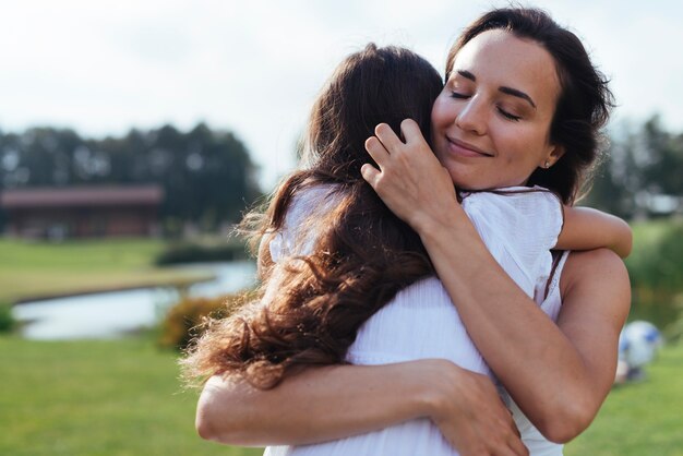 Mãe amorosa, abraçar, filha, ao ar livre