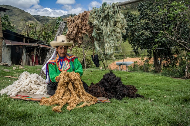 Mãe andina latino-americana secando lã colorida para a técnica inca de tecelagem peruana Foto Premium