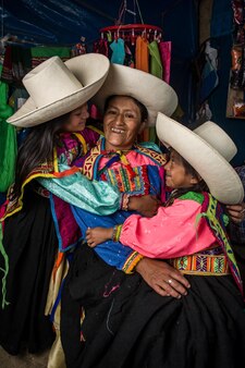 Mãe andina peruana ensinando suas filhas a tecer e a fazer fios e a posar para sorrir