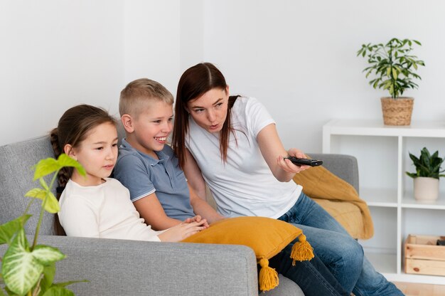 Mãe assistindo televisão com seus filhos