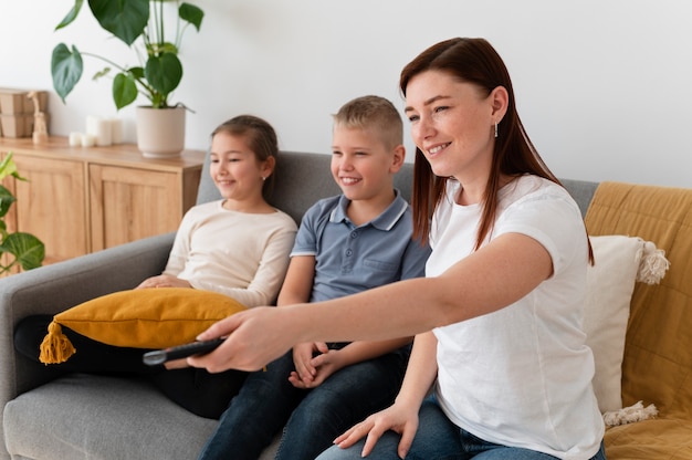 Mãe assistindo televisão com seus filhos