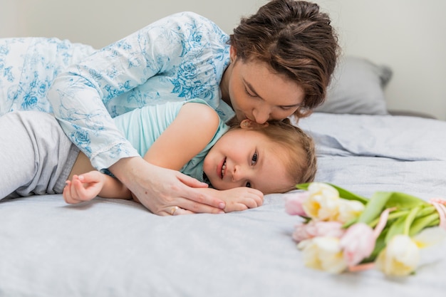 Mãe beijando a filha inocente na cama