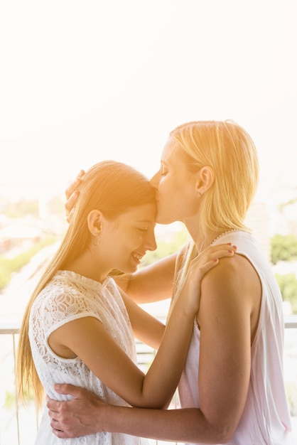 Mãe beijando a filha na testa