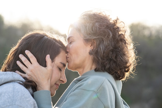 Foto grátis mãe beijando a testa da filha ao ar livre