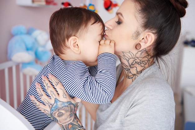 Mãe beijando filho sonolento na testa