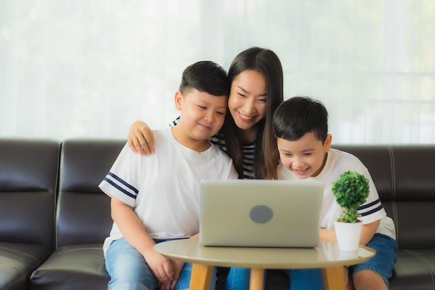 Mãe bonita jovem asiática com seus filhos usando um laptop