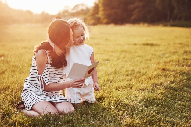 Mãe brinca com a filha na rua no parque ao pôr do sol