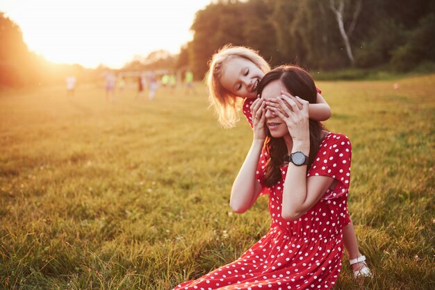 Mãe brinca com a filha na rua no parque ao pôr do sol