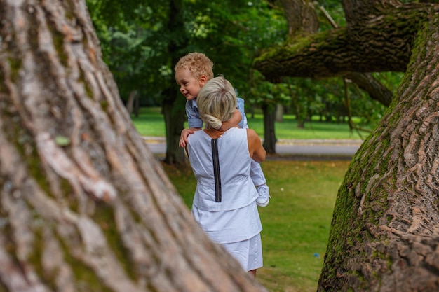 Mãe brincando com seu filho na árvore no parque outono.