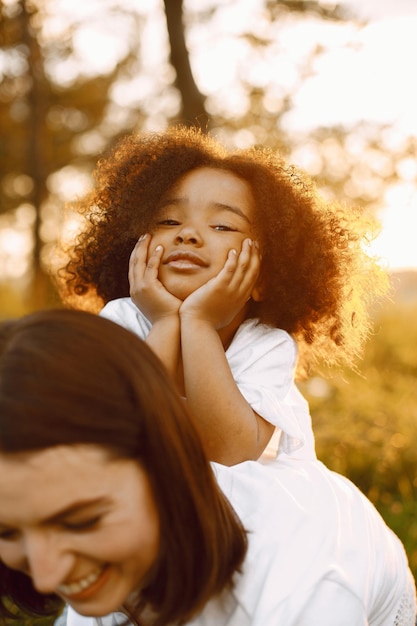 Foto grátis mãe caucasiana segurando a filha afro-americana nas costas