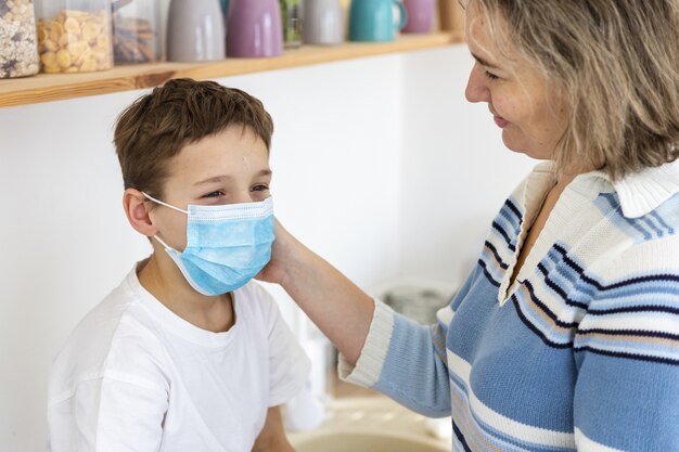 Mãe colocando máscara médica em seu filho