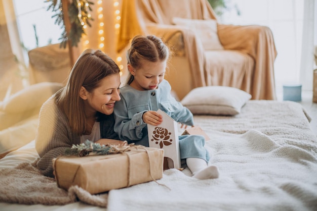 Mãe com a filha embalando presentes de natal e se divertindo