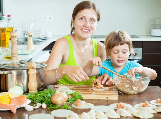 mãe com a filha fazendo um maravilhoso bolinho de peixe na cozinha doméstica