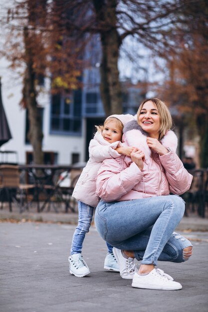 Mãe com a filha pequena, vestida com um pano quente fora da rua