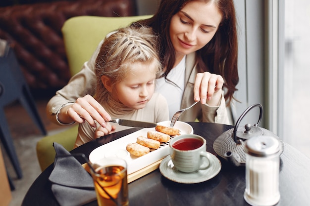 Mãe com a filha sentada em um café