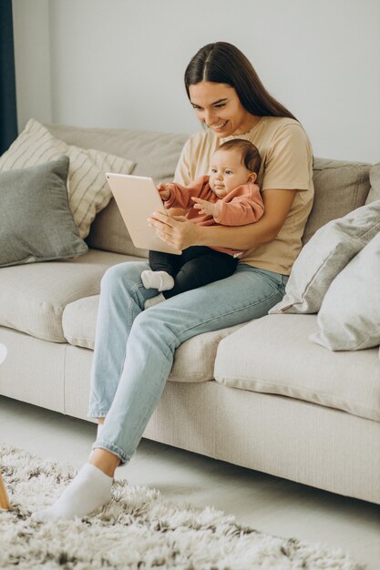 Mãe com a menina bbay usando o tablet em casa