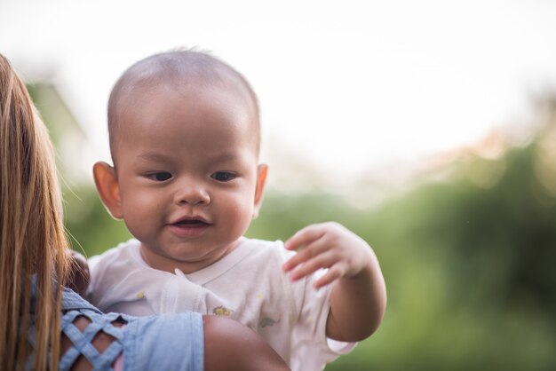 Mãe com bebê, rindo e brincando no parque