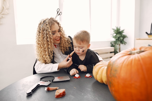 Mãe com criança em fantasias e maquiagem. Família se prepara para a celebração do Halloween.