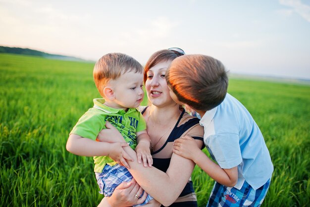 Mãe com dois filhos em campo verde