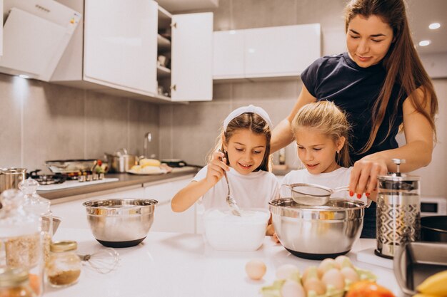 Mãe com duas filhas na cozinha assar