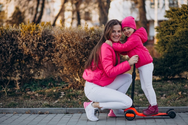 Mãe com filha andando de scooter elétrica