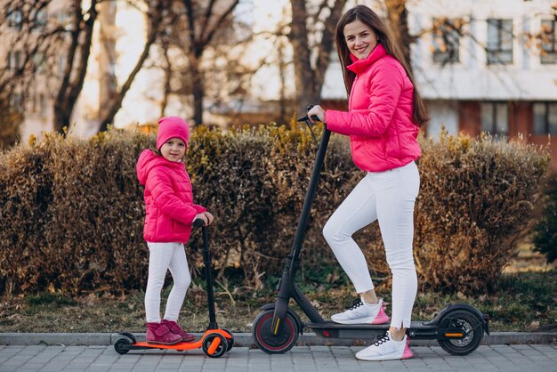 Mãe com filha andando de scooter elétrica