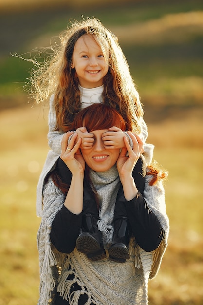 Mãe com filha brincando em um campo de outono