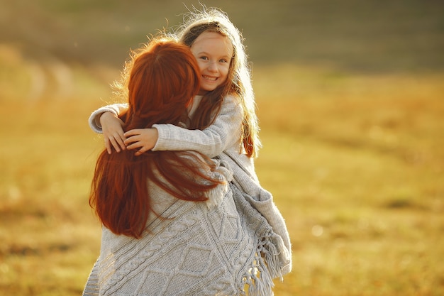 Mãe com filha brincando em um campo de outono