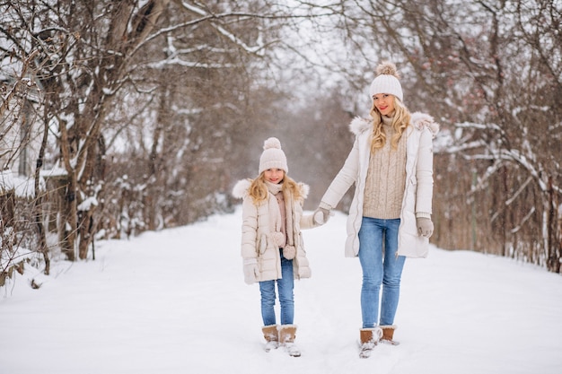 Mãe com filha caminhando juntos em um parque de inverno