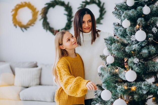 Mãe com filha decorando árvore de natal