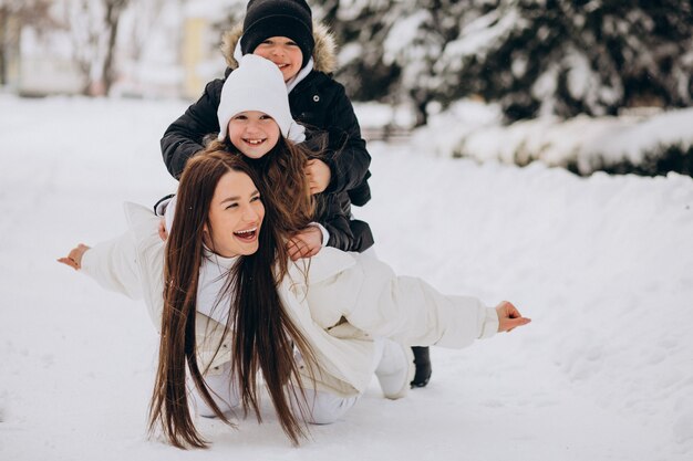 Mãe com filha e filho se divertindo em um parque cheio de neve