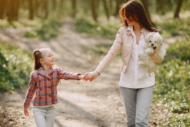 Mãe com filha em uma floresta de primavera com cachorro