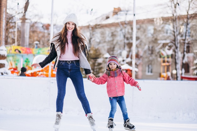 Mãe com filha ensinando patinação no gelo em uma pista