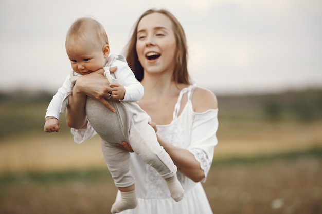 Mãe com filha. Família em um campo. Menina recém-nascida. Mulher de vestido branco.