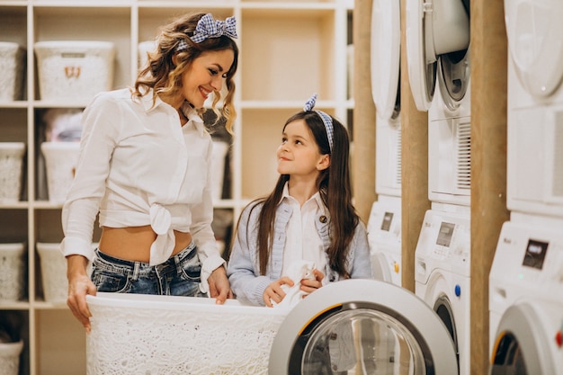 Foto grátis mãe com filha lavando roupa na lavanderia self-service
