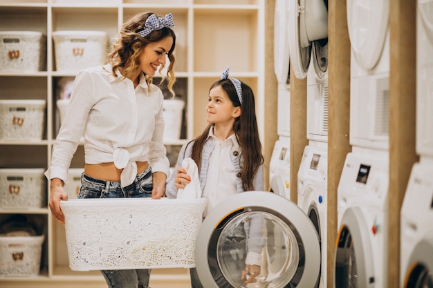 Foto grátis mãe com filha lavando roupa na lavanderia self-service