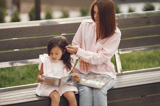 Mãe com filha lendo um livro na cidade