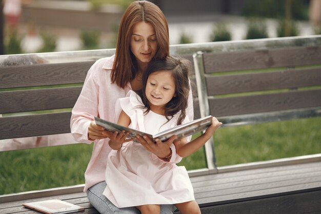 Mãe com filha lendo um livro na cidade