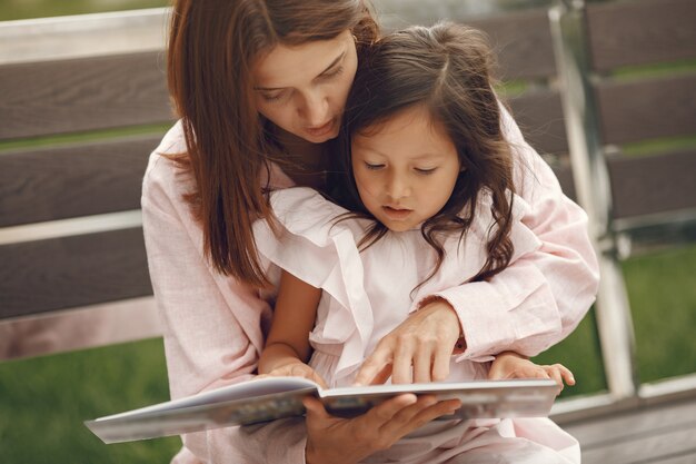 Mãe com filha lendo um livro na cidade