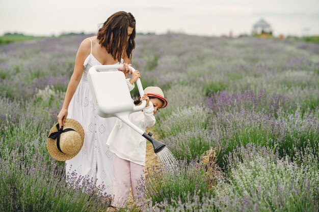 Mãe com filha no campo de lavanda. Mulher bonita e bebê fofo brincando no campo do Prado. Férias em família num dia de verão.