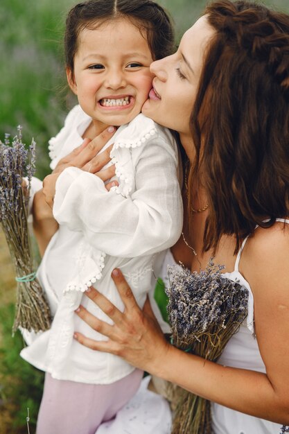 Mãe com filha no campo de lavanda. Mulher bonita e bebê fofo brincando no campo do Prado. Férias em família num dia de verão.