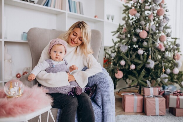 Mãe com filha pequena pela árvore de Natal