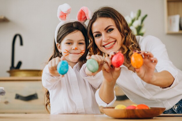 Mãe com filha pintando ovos para a Páscoa